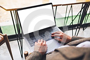 A woman using and typing on laptop computer with blank white desktop screen