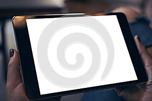 Mockup image of a woman wearing ripped jean sitting cross legged , holding black tablet pc with blank white desktop screen