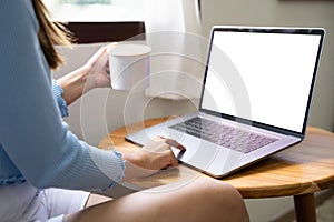 Mockup image of a woman working and typing on laptop computer with blank white screen at home