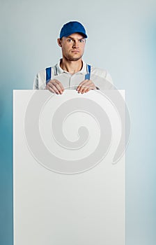 Mockup image of a young indignant worker holding empty white banner. White or blue background. Bussines concept