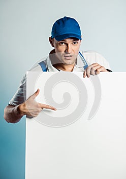 Mockup image of a young worker holding empty white banner and points to it
