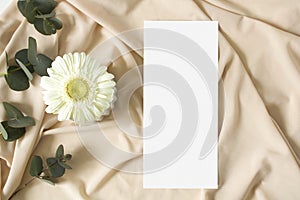 Mockup menu card with eucalyptus leaves on the nude fabric