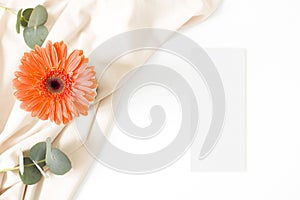 Mockup menu card with gerbera leaves and nude fabric