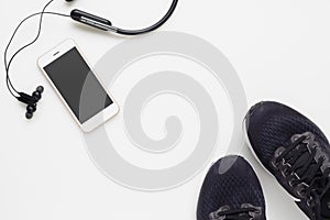 Mockup mobile cellphone with wireless bluetooth earphone and running shoes on white background. Healthy active lifestyles