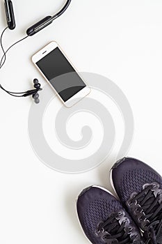 Mockup mobile cellphone with wireless bluetooth earphone and running shoes on white background. Healthy active lifestyles