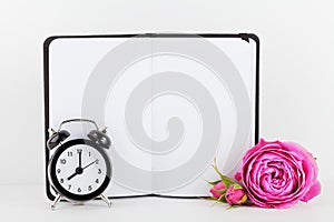 Mockup of notebook decorated rose flower and alarm clock on white background with clean space for text and design your blogging.