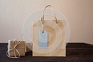 Mockup Paper bag from kraft paper with gift tag and Christmas gift boxes on a wooden background