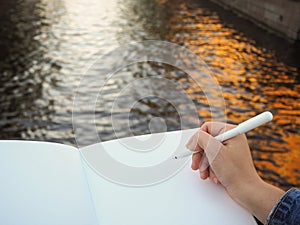 Mockup of person`s hand holding blank white notebook preparing to write down his or hers ideas.