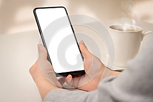 Mockup phone. Close up hand holding cellphone smartphone with blank screen in coffee shop. Woman hand using mock up smart phone at