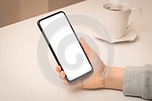 Mockup phone. Close up hand holding cellphone smartphone with blank screen in coffee shop. Woman using mock up mobile phone while
