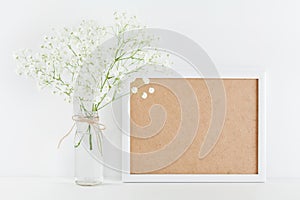 Mockup of picture frame decorated flowers in vase on white working desk with clean space for text and design your blogging.