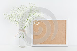Mockup of picture frame decorated flowers in vase on white working desk with clean space for text and design your blogging. photo
