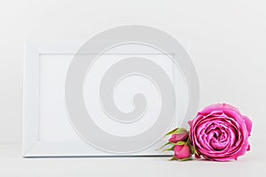 Mockup of picture frame decorated rose flower on white desk with clean space for text and design your blogging.