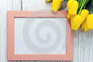 Mockup of picture frame decorated yellow tulip flowers on wooden background. Styled stock photography