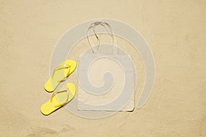 Mockup shopper handbag beach sand background. Top view copy space shopping eco reusable bag. Flip flops accessories. Template