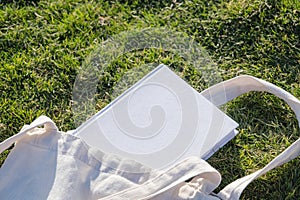 Mockup shopper handbag and book, green grass background