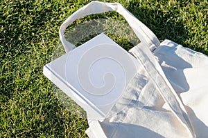 Mockup shopper handbag and book, green grass background
