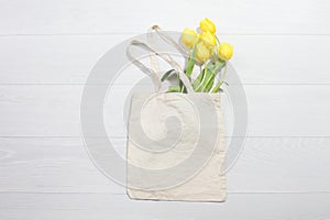 Mockup shopper handbag. Yellow tulips. Wood background. Top view copy space shopping eco reusable bag. Mothers women day. Template