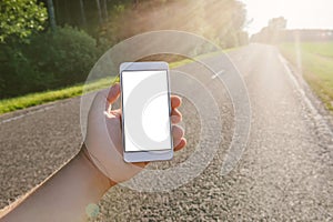 A mockup of a smartphone in the hand of a guy. Against the background of the road, the sun