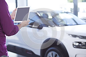 Mockup of tablet of car seller in dealing salon with extravagance vehicles