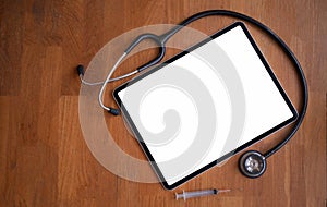 Mockup of tablet , stethoscope and syringe on wooden floor