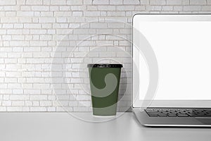 Mockup template laptop computer display screen and cup with blank on desk, workplace and office.