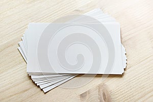 Mockup template with many white cards stacked and rotated on light wooden surface