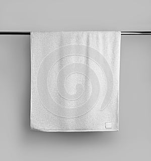 Mockup of a terry white towel with a label on a metal bar, hanging towelling for design, branding