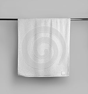Mockup of a terry white towel with a label on a metal bar, hanging towelling for design, branding photo
