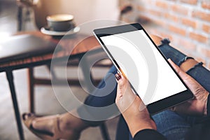 Mockup top view image of a woman wearing ripped jean sitting cross legged , holding black tablet pc with blank white desktop scree