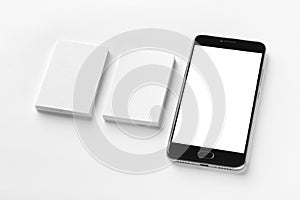 Mockup of two vertical business cards and black cell-phone with blank screen at white textured paper background.