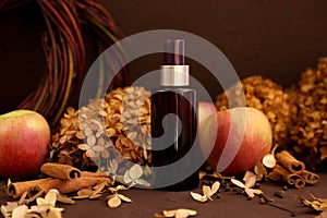 Mockup of unbranded brown spray bottle, cinnamon, autumn apples and dry hydrangea flowers on dark brown background  Cosmetic