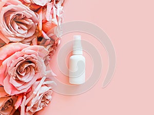 Mockup of unbranded white plastic spray bottle and pink roses on a pastel pink background. Bottle for branding and label.