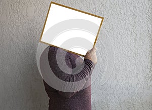 mockup. unrecognizable man holding behind head white blank picture photo frame. mock up template. male holding image frame on