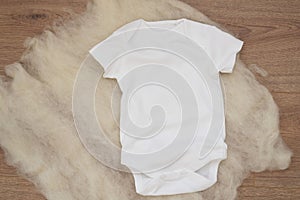 Mockup of white baby bodysuit on wood background. Blank baby clothes template mock up. Flat lay styled stock photo