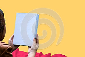 Mockup of a white blank hardcover book featuring a woman reading on summer themed orange background