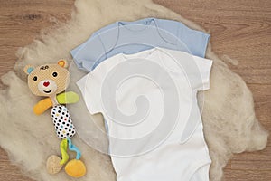 Mockup of white and blue baby bodysuit on wood background and colorful bear toy. Blank baby clothes template mock up. Flat lay