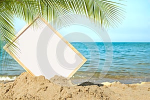 Mockup white board on sand beach with leaves palm or coconut palm