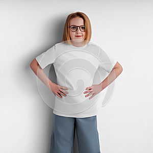 Mockup of white children\'s shirt, close-up, t-shirt on posing girl, clothes isolated on background in studio