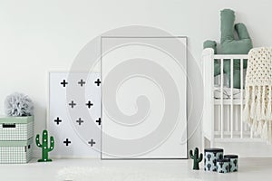 Mockup of white empty poster next to cradle in kid`s room interi