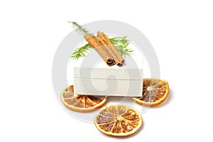 Mockup white gift box with dried orange fruits, cinnamon stick, cone, sprig of spruce Christmas tree on white background.