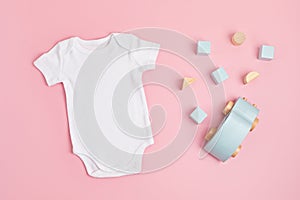 Mockup of white infant bodysuit made of organic cotton with eco friendly baby toys photo