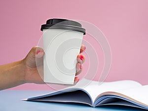 Mockup white paper coffee cup to go with a opened magazine. Side view on blue background. Copy Space for text