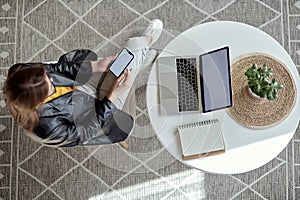 Mockup white screen laptop and mobile phone woman using computer sitting at table at home, top view