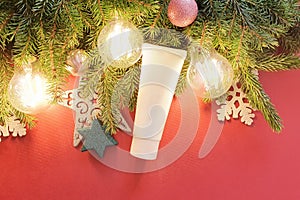 Mockup of white squeeze bottle plastic tube, fir tree, stars, balls and magic lights on red background. Top view, flat lay style