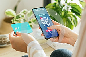 Mockup of a woman paying an order online with the phone and a credit card from home