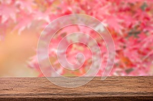 Mockup wood table for product display with blurred red and pink maple leaves background