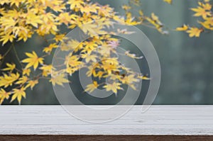 Mockup wood table for product display with blurred yellow maple leaves background