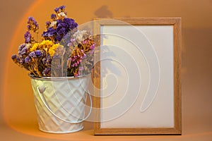 Mockup Wooden frame with Empty white paper blank and delicate dry flowers in white bucket on beige background. Minimal