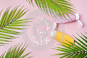 Mockup of Yellow and Pink cosmetic tube with sunscreen Cream in the form of sun SPF on pink background Copy Space Leaf Top View